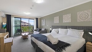 Une chambre d’hôtel avec un grand lit, un bureau, une chaise et un balcon avec vue.
