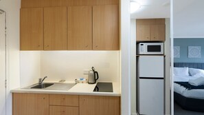 Une cuisine compacte dotée de meubles en bois, d’un évier, d’une bouilloire, d’un four à micro-ondes et d’un réfrigérateur.