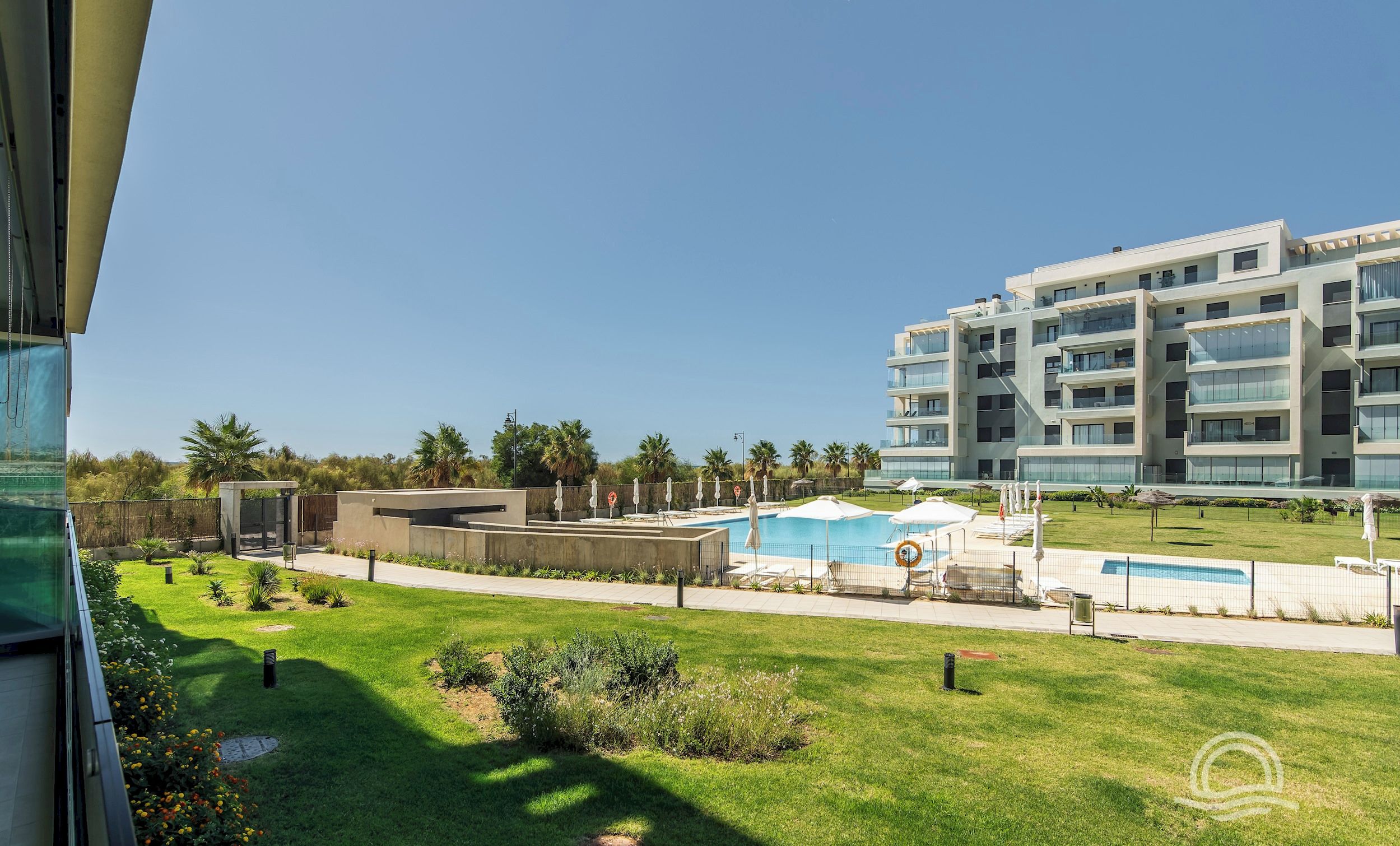 Un hôtel moderne doté d’une piscine, d’une pelouse bien entretenue et d’un bâtiment à plusieurs étages en arrière-plan.
