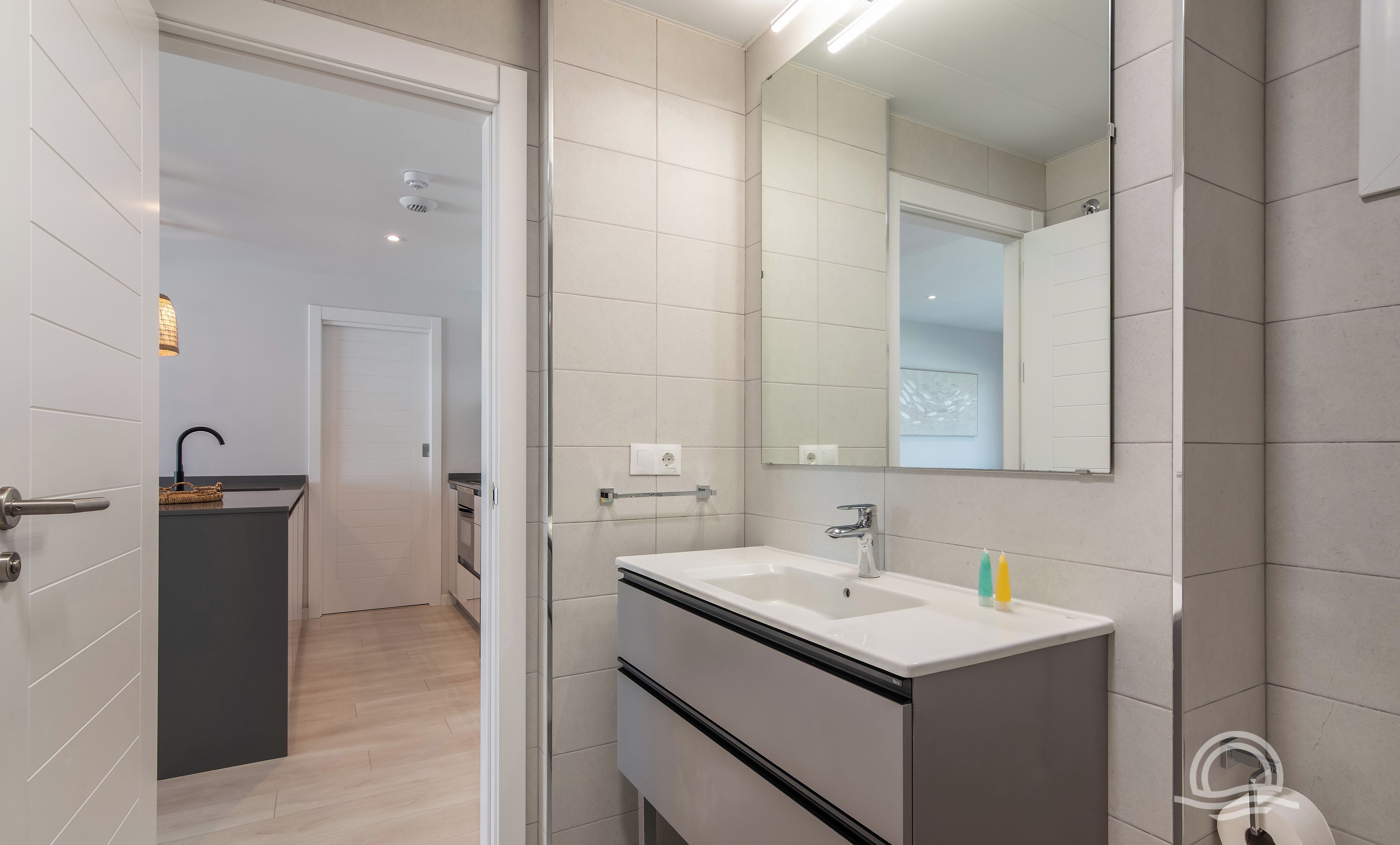 Un baño moderno con un espejo grande, un lavabo y una zona de ducha.
