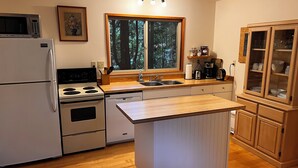 Una cucina compatta con frigorifero, fornello, lavello e pensili in legno.