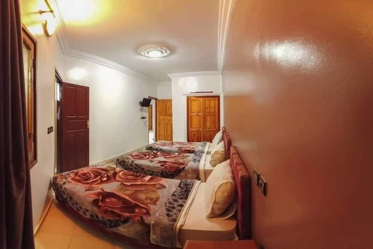 Un pasillo estrecho que conduce a un dormitorio con dos camas, puertas de madera y una lámpara en el techo.