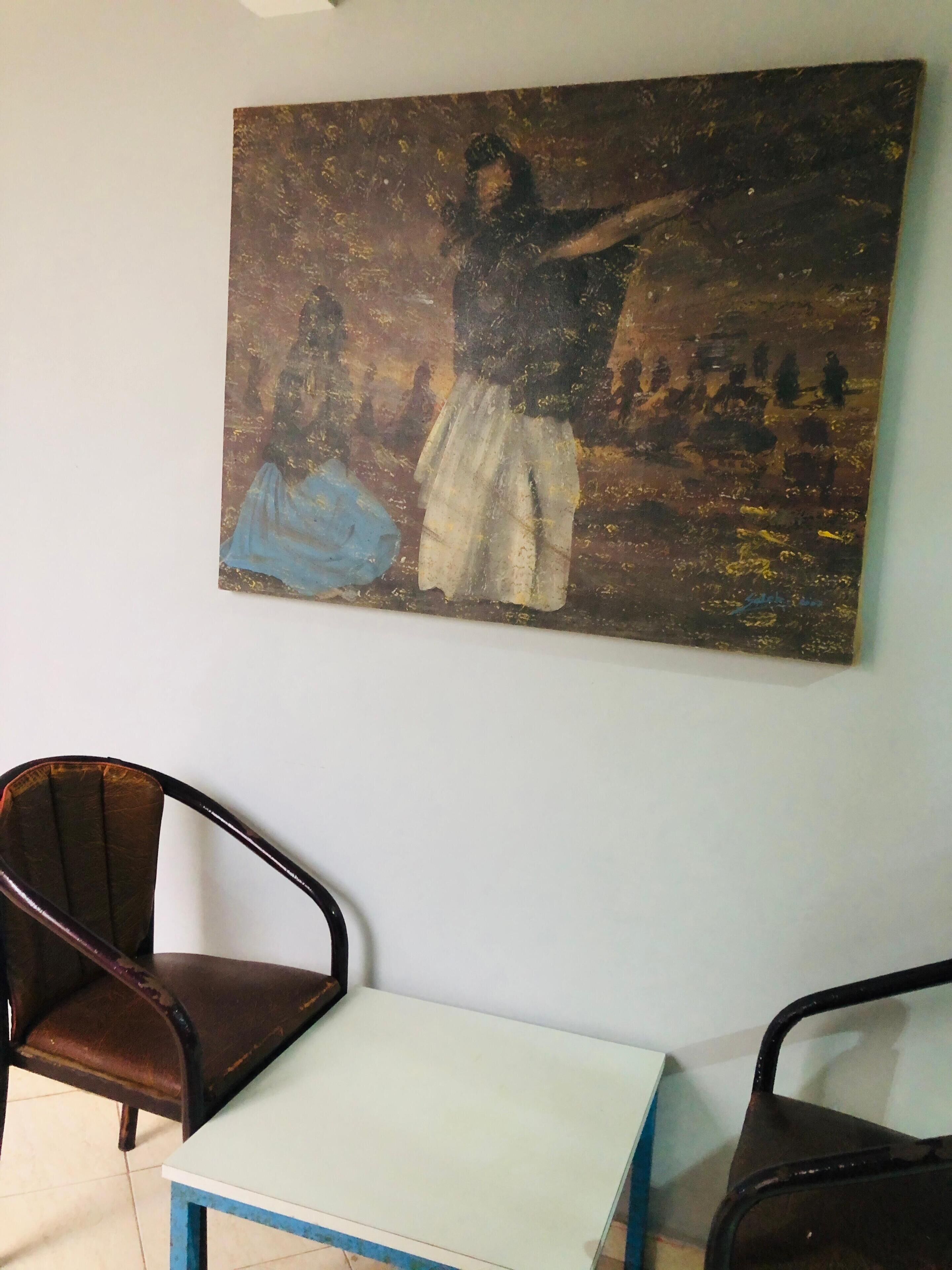 Une pièce avec un tableau au mur, une table et deux chaises.