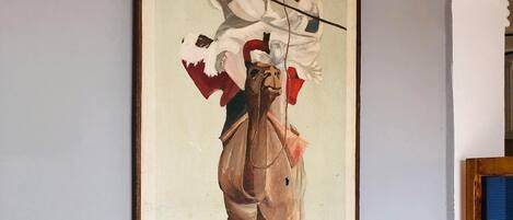 A framed painting of a person riding a camel.