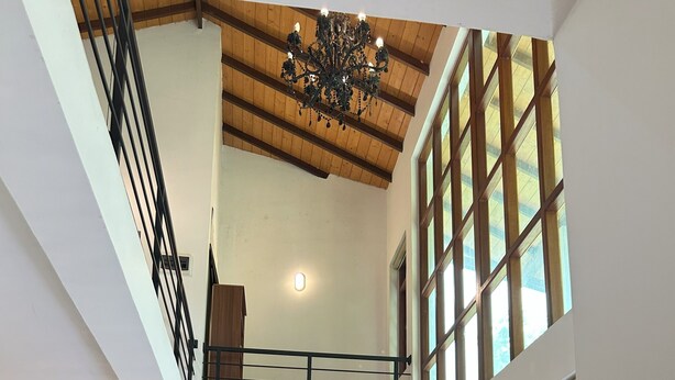 A spacious living area with a piano, a large sofa, and a dining table.