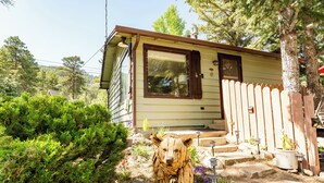 A small house with a wooden fence and a bear sculpture in the front yard.