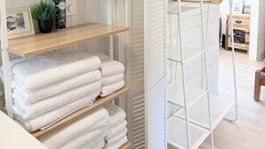 A neatly organized bathroom with white fixtures, a towel rack, and a shelf with toiletries.
