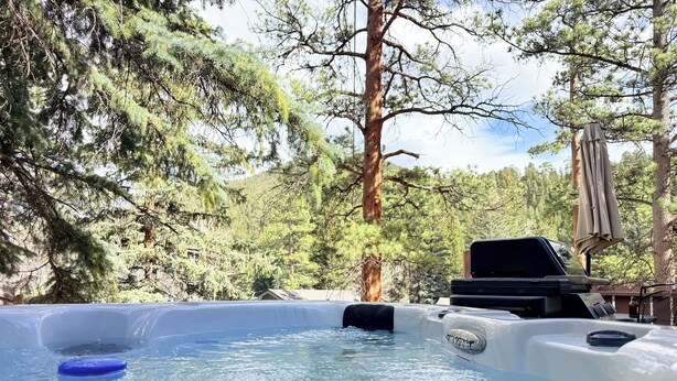 A hot tub in a natural setting with trees and a wooden deck.