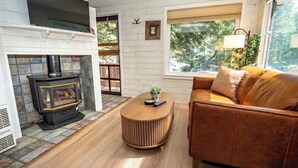A living room with a fireplace, a sofa, a coffee table, and a TV mounted above the fireplace.