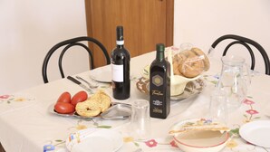 A dining table set with plates, cutlery, a bottle of wine, bread, and a pitcher of water.