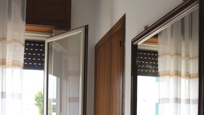 A room with a sliding glass door, a wooden door, and a window with curtains.
