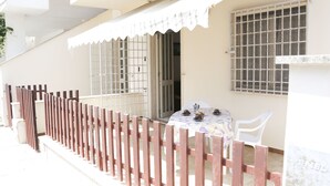 A balcony with a wooden fence, a table with chairs, and a window with bars.