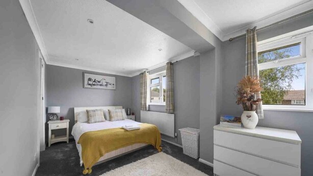 A bedroom with a bed, bedside table, dresser, window, and a view of the outside. - 5 Bed House - Sleeps 10 - Garden - Parking - Wifi (Aylesford)