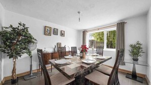 A dining area with a marble table, chairs, and a potted plant. - 5 Bed House - Sleeps 10 - Garden - Parking - Wifi (Aylesford)