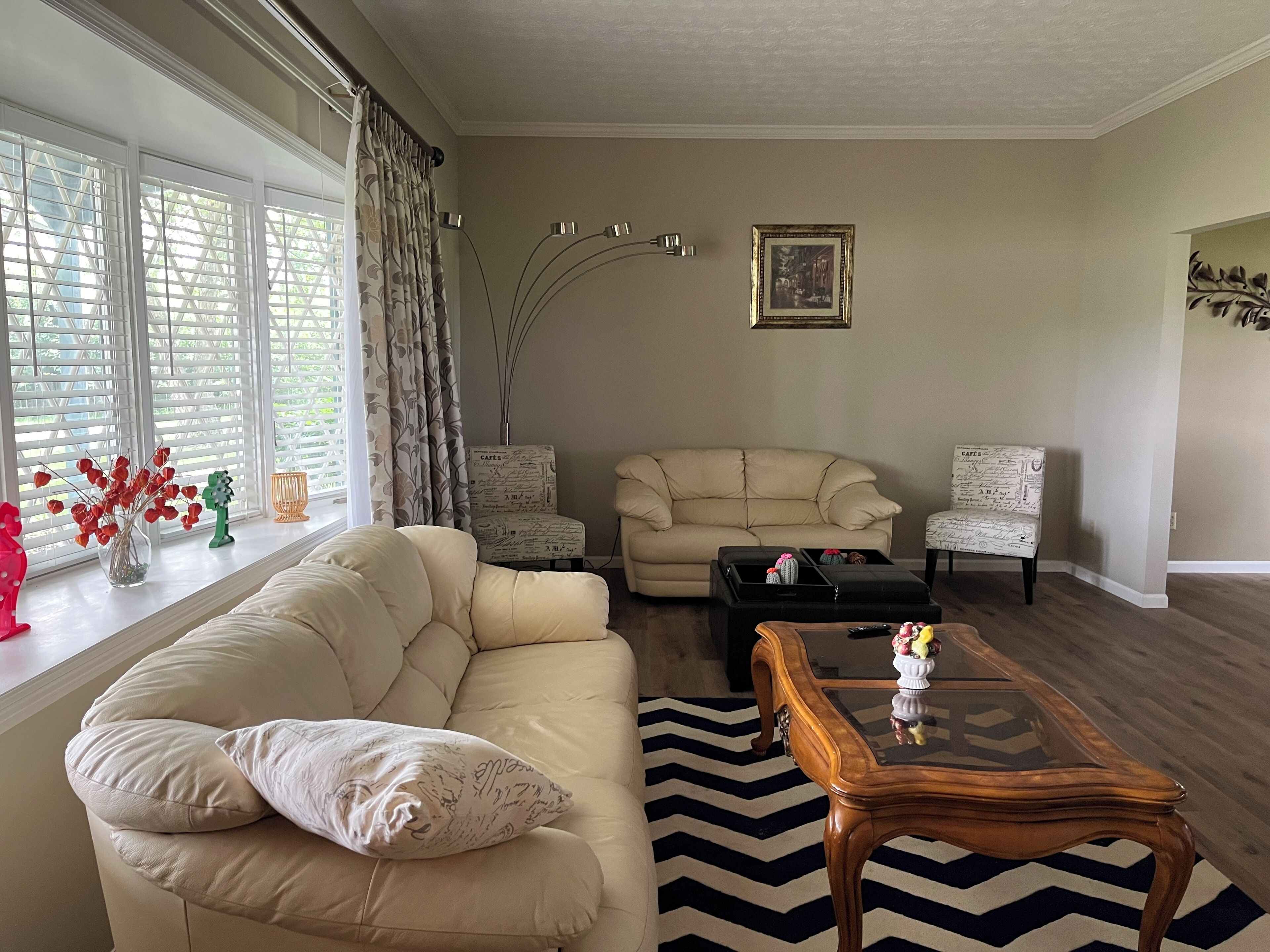 A living room with a beige sofa, two armchairs, a coffee table, and a rug.