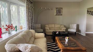 A living room with a beige sofa, two armchairs, a coffee table, and a rug.