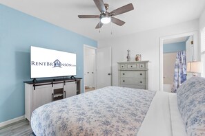 Un dormitorio con cama, cómoda, televisor y ventilador de techo.