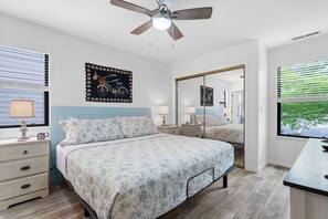 A bedroom with a bed, bedside tables, a ceiling fan, and a window with blinds.