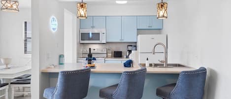 Una cocina moderna con una isla central, taburetes de bar e iluminación colgante.