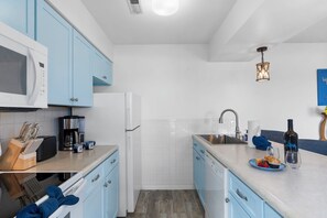 Eine moderne Küche mit blauen Schränken, einer Mikrowelle, einer Kaffeemaschine und einem Spülbecken.