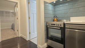 A kitchen with dark wood flooring, a stainless steel oven, and a dishwasher. - Discerning Accommodation in Thorndon (Wellington)