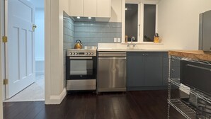 A modern kitchen with a built-in oven, dishwasher, and a kettle on the countertop. - Discerning Accommodation in Thorndon (Wellington)