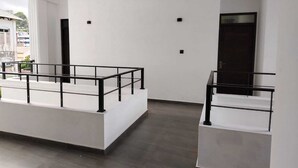 A modern interior with a minimalist design, featuring a spacious balcony area with a metal railing and a dark-toned door. - DIORA Hotel (Ratnapura)