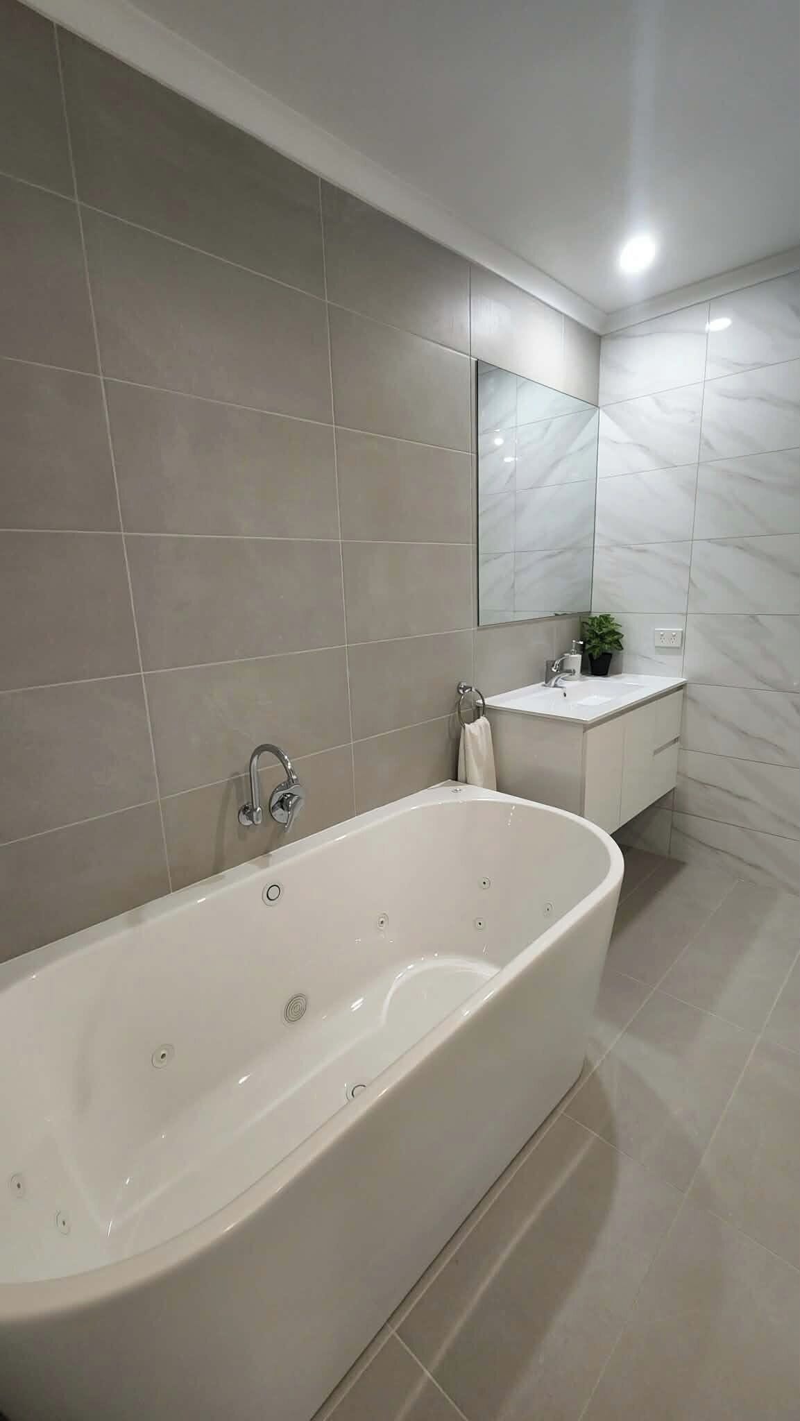Un baño moderno con una bañera independiente, un lavabo y un espejo sobre él.