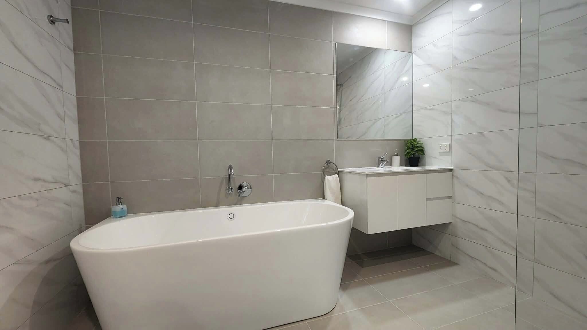 A modern bathroom with a freestanding bathtub, a sink with a mirror above it, and a potted plant on the countertop.