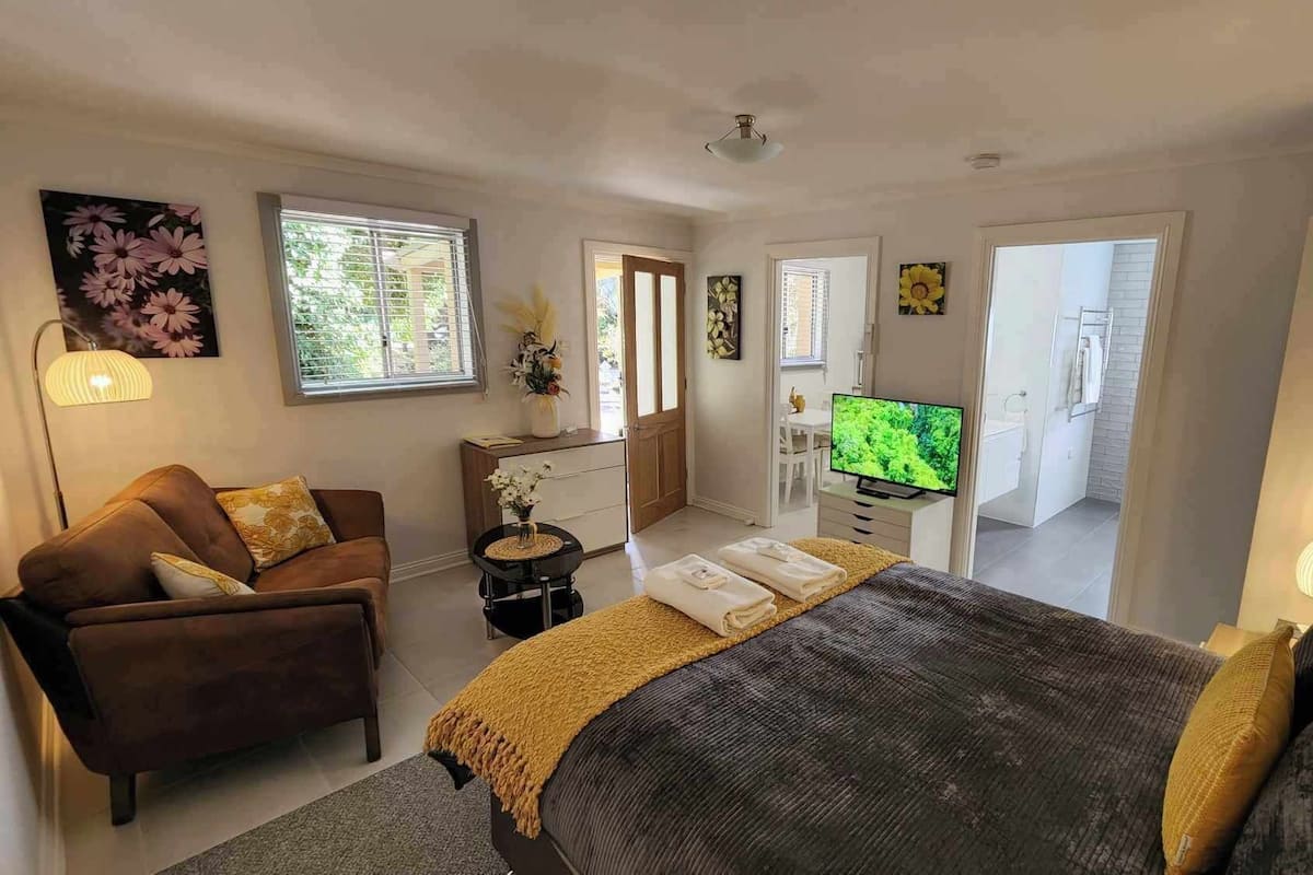 Une chambre à coucher moderne avec un lit, un canapé, une télévision et un bureau.
