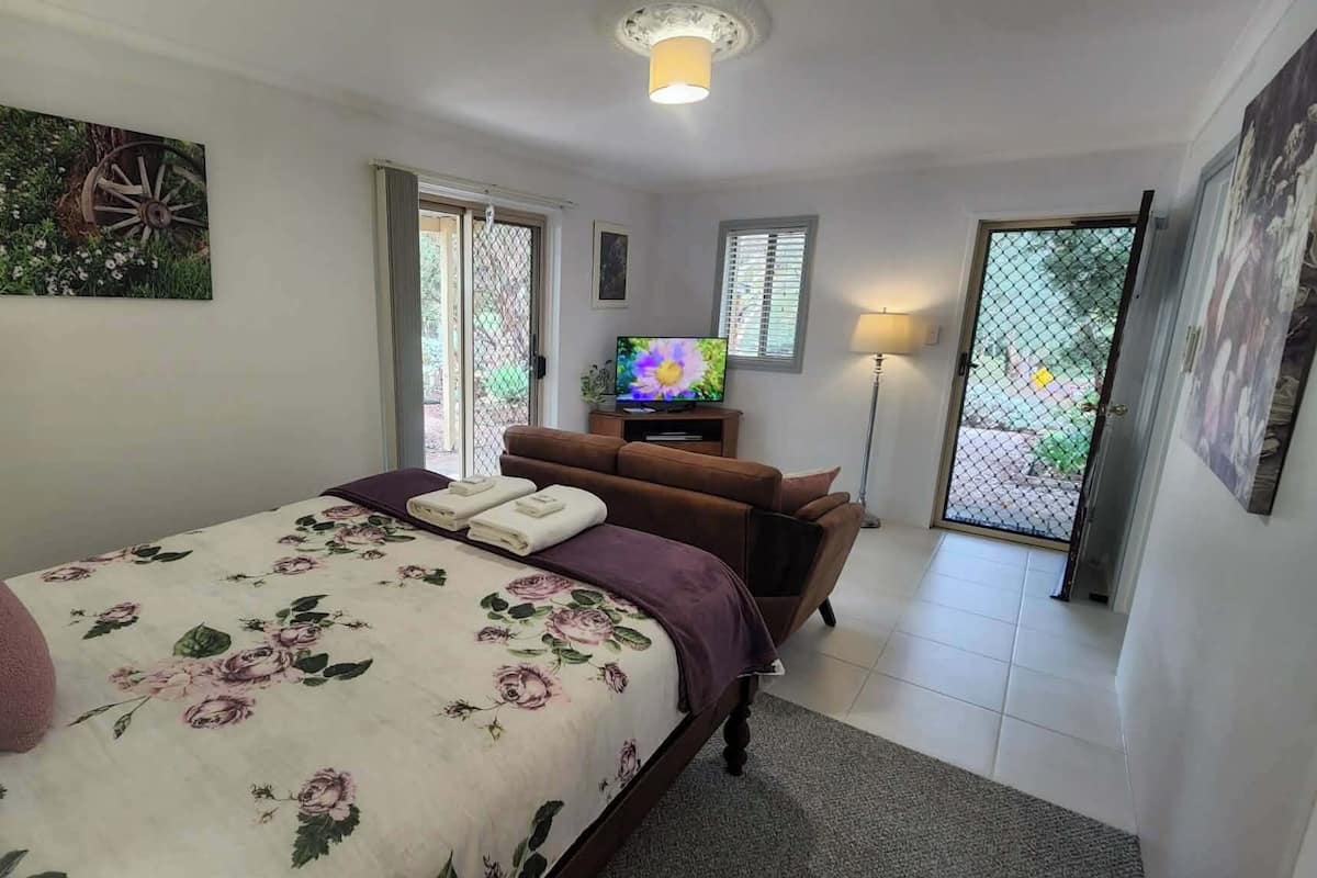 Une chambre avec un lit, une télévision, un canapé et un tableau accroché au mur.