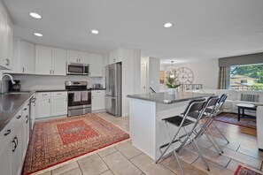 A modern kitchen with white cabinets, stainless steel appliances, and a red patterned rug.