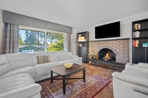 A modern living room with a fireplace, a sofa, a coffee table, and a bookshelf.