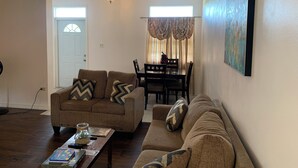 Un salon comprenant un canapé, une table basse et un coin repas avec une table et des chaises.