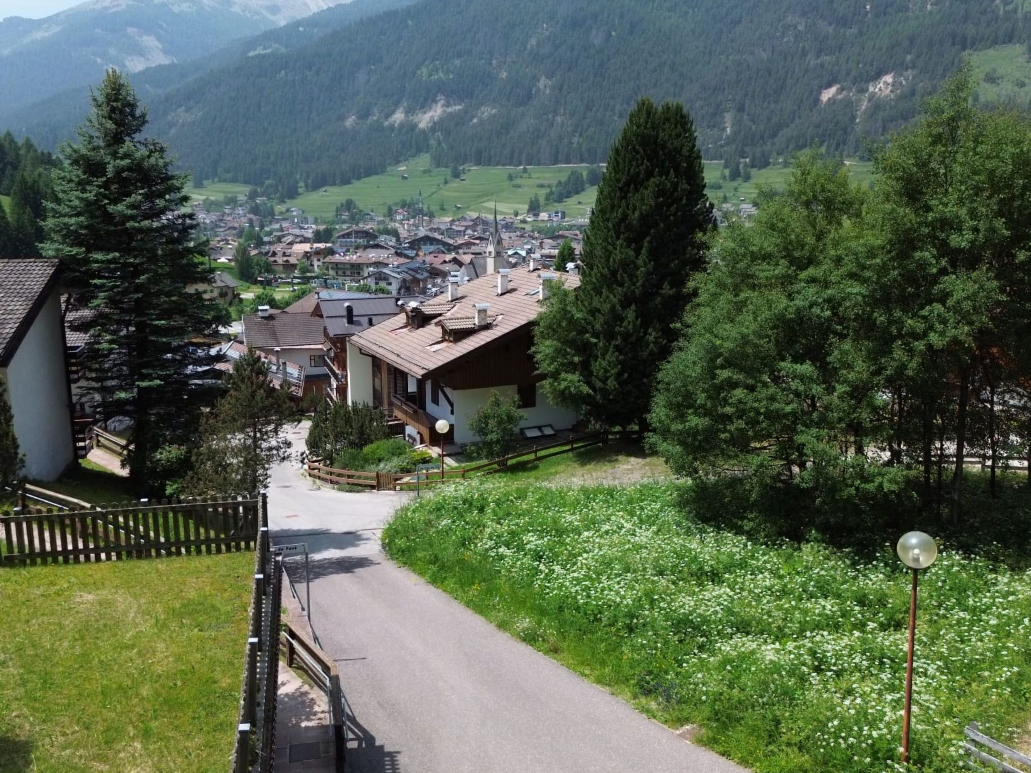 A mountain village with traditional architecture, a paved road, and a view of the village and mountains in the distance.