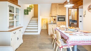 Una cocina con armarios de madera, una mesa de comedor con platos y una escalera que lleva a otra habitación.