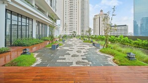 A modern urban courtyard with a wooden deck, stone pathway, and lush greenery.