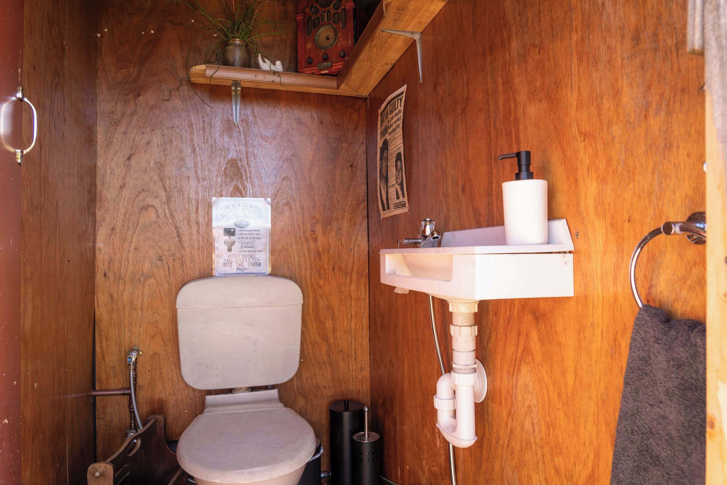 Un baño de madera con inodoro, lavamanos y una planta colgante.