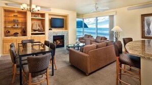 A hotel room with a dining area, a living room with a sofa and chairs, a fireplace, a television, and a large window with a view of the ocean. - Oceanfront Penthouse Condo, Worldmark Seaside Resort; Nights 5, 6 & 7 only 50 (Seaside)