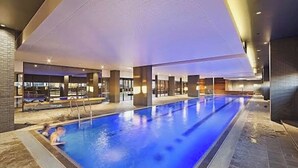 A large indoor swimming pool with a clear view of the pool area, surrounded by modern architecture and a well-lit interior. - Central CBD Location | Pool & Gym | 2BR 2Bath (Melbourne)