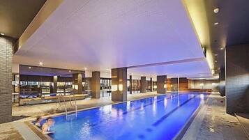 A large indoor swimming pool with a clear view of the pool area, surrounded by modern architecture and a well-lit interior.