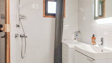 Ein modernes Badezimmer mit Dusche, kleinem Fenster und Waschbecken mit einer Seife.
