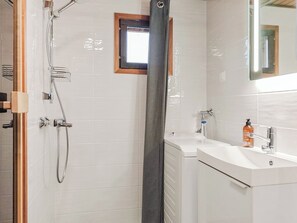 Une salle de bain moderne avec une douche, une petite fenêtre et un lavabo avec un savon.