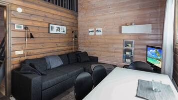 Un salon moderne avec un canapé d’angle, une table à manger et un téléviseur à écran plat.