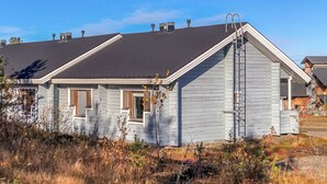 Una casa de dos pisos con techo oscuro, una chimenea visible y una escalera en el lateral.