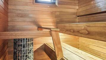 Eine Holzsauna mit einer Sitzbank, einem Fenster und einer Uhr an der Wand.