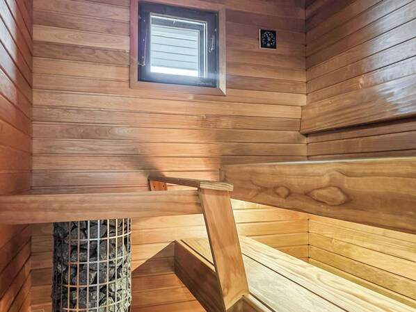 Un sauna en bois avec un banc, une fenêtre et une horloge au mur.