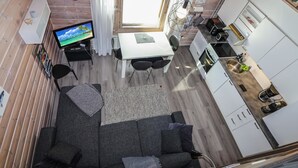 Una habitación compacta con sofá, mesa de comedor, televisor y zona de cocina.