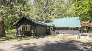 A cabin with a metal roof, a front porch, and a gravel driveway. - 3-bedroom pet friendly cabin with WiFi, hottub and AC in Mount Hood Village (Mount Hood Village)