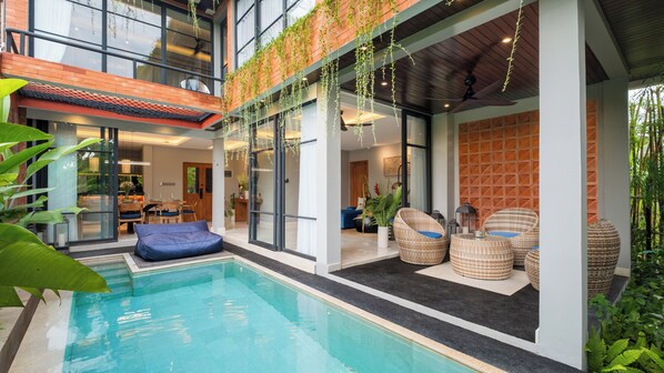 Una casa moderna con piscina, area salotto esterna e zona pranzo.